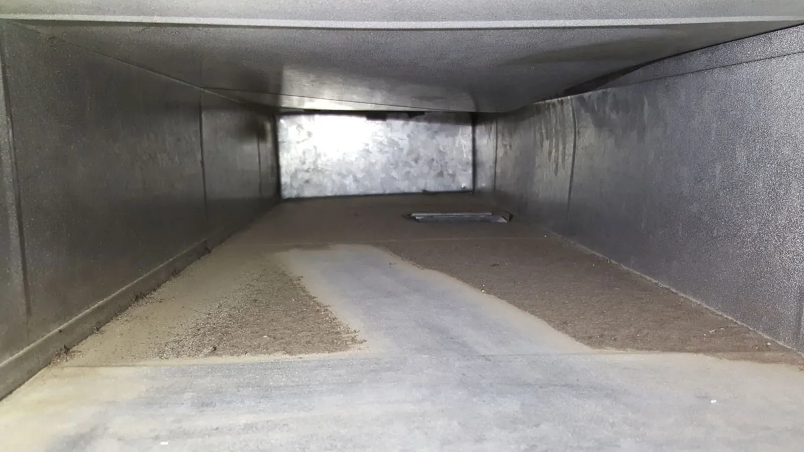 Inside of an air duct coated with dust before cleaning