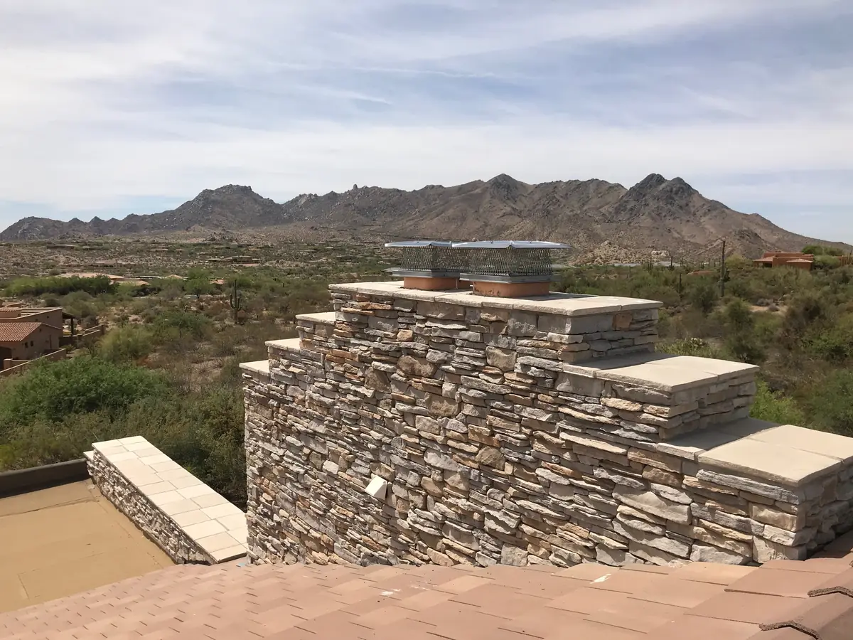 Chimney cap on a stacked-stone chimney with mountain views