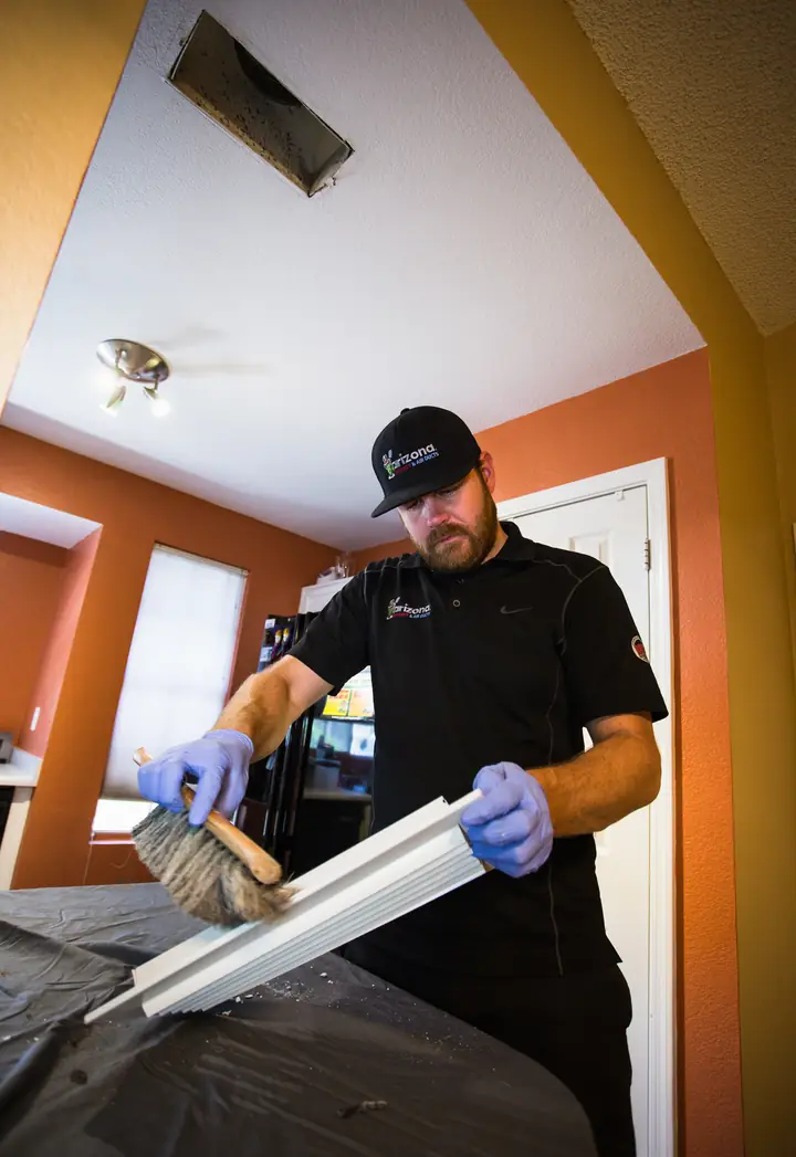 Technician cleaning a return air register