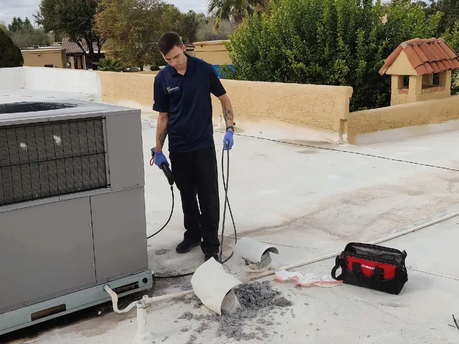 Technician cleaning a rooftop dryer vent