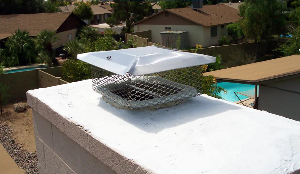 Stainless steel chimney cap on a white masonry chimney