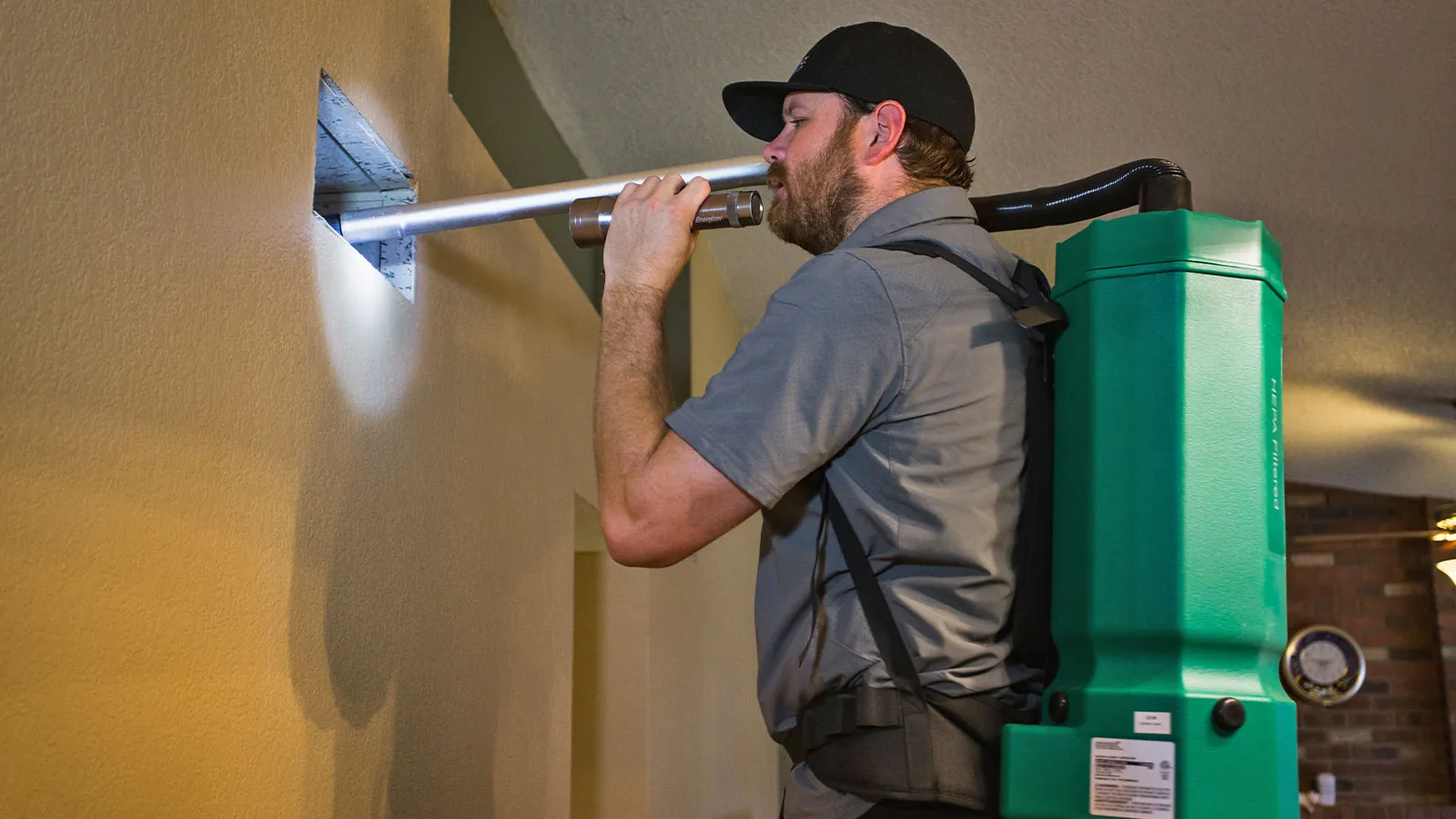 Technician cleaning an air vent with a backpack HEPA vacuum in a Phoenix home