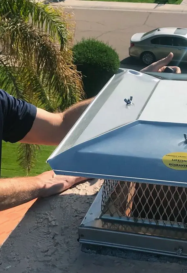 Technician fitting a stainless steel chimney cap